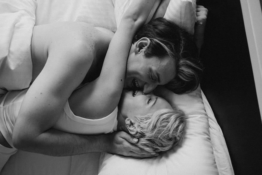 Loving cpuple laying on bed while embracing and kissing