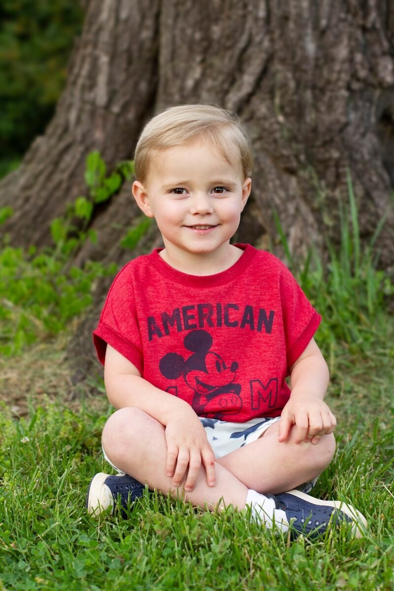 a little boy that is sitting in the grass