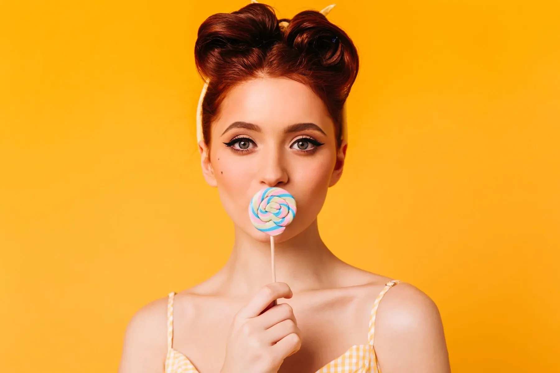 Joyful ginger woman licking lollipop appealing female model