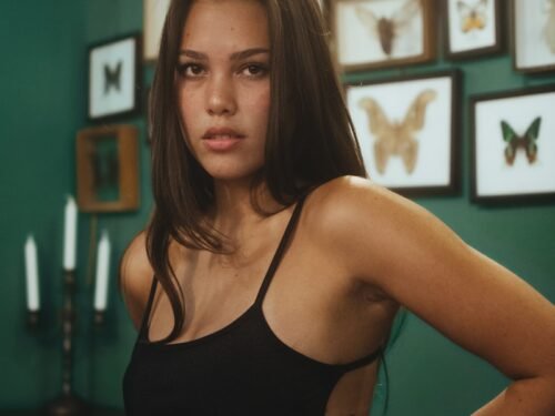 a beautiful young woman in a black bikini posing for a picture