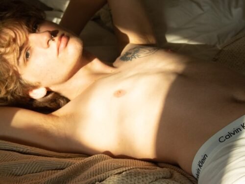 a shirtless man laying on a bed