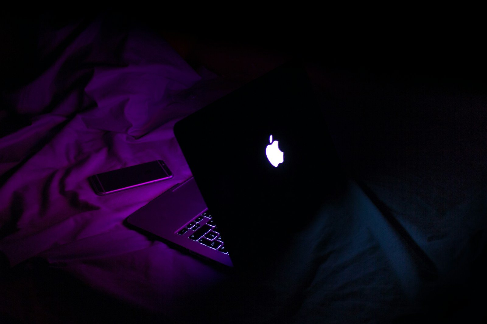 silver MacBook beside smartphone