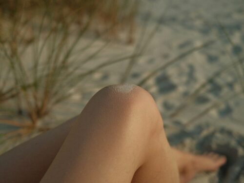 Close-up of a person's legs on a sandy beach.