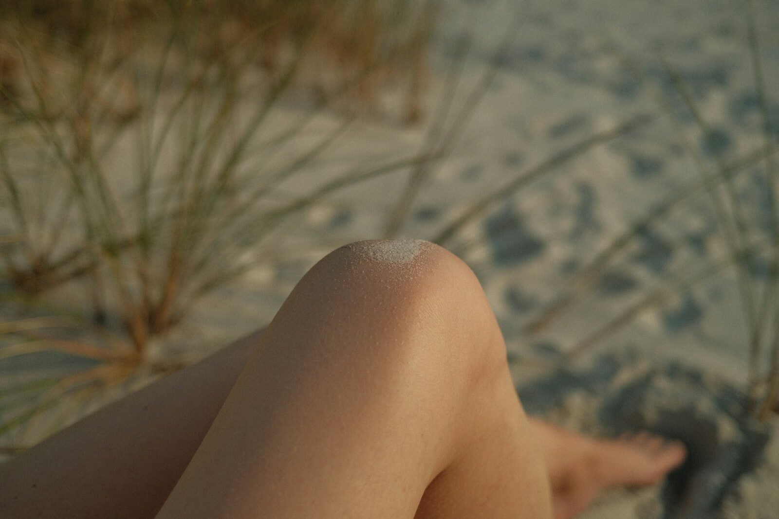 Close-up of a person's legs on a sandy beach.