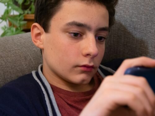 a young man sitting in a chair looking at a cell phone