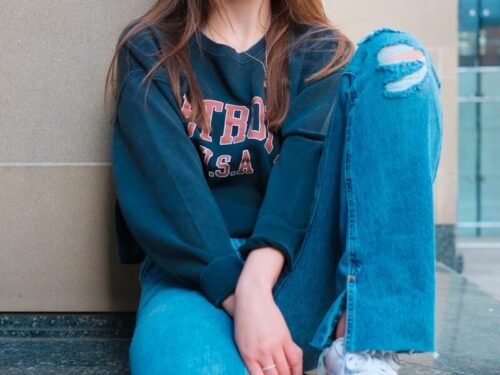 a woman sitting on a ledge with her legs crossed