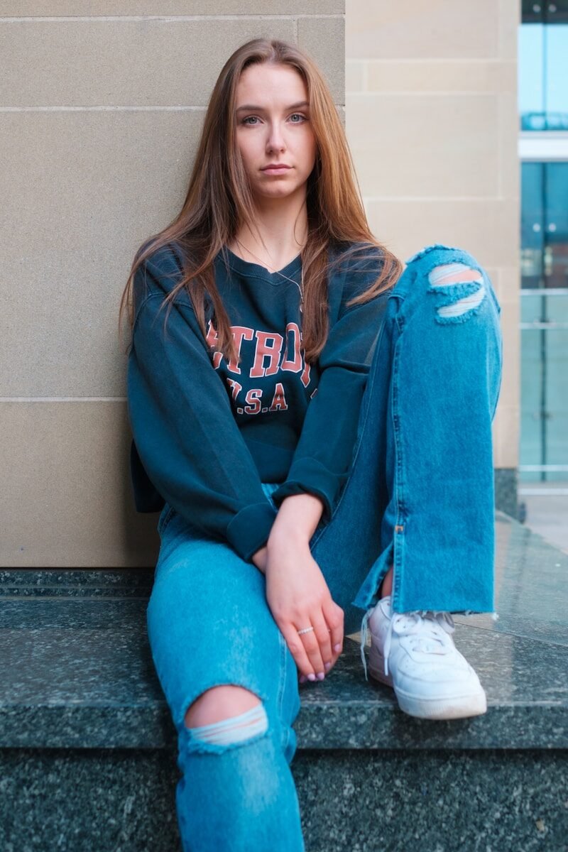 a woman sitting on a ledge with her legs crossed