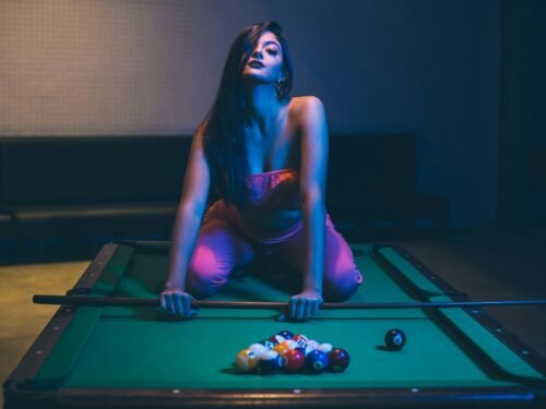 woman in purple tank top and pink leggings sitting on billiard table