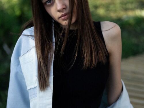 A young woman poses, looking directly at you.