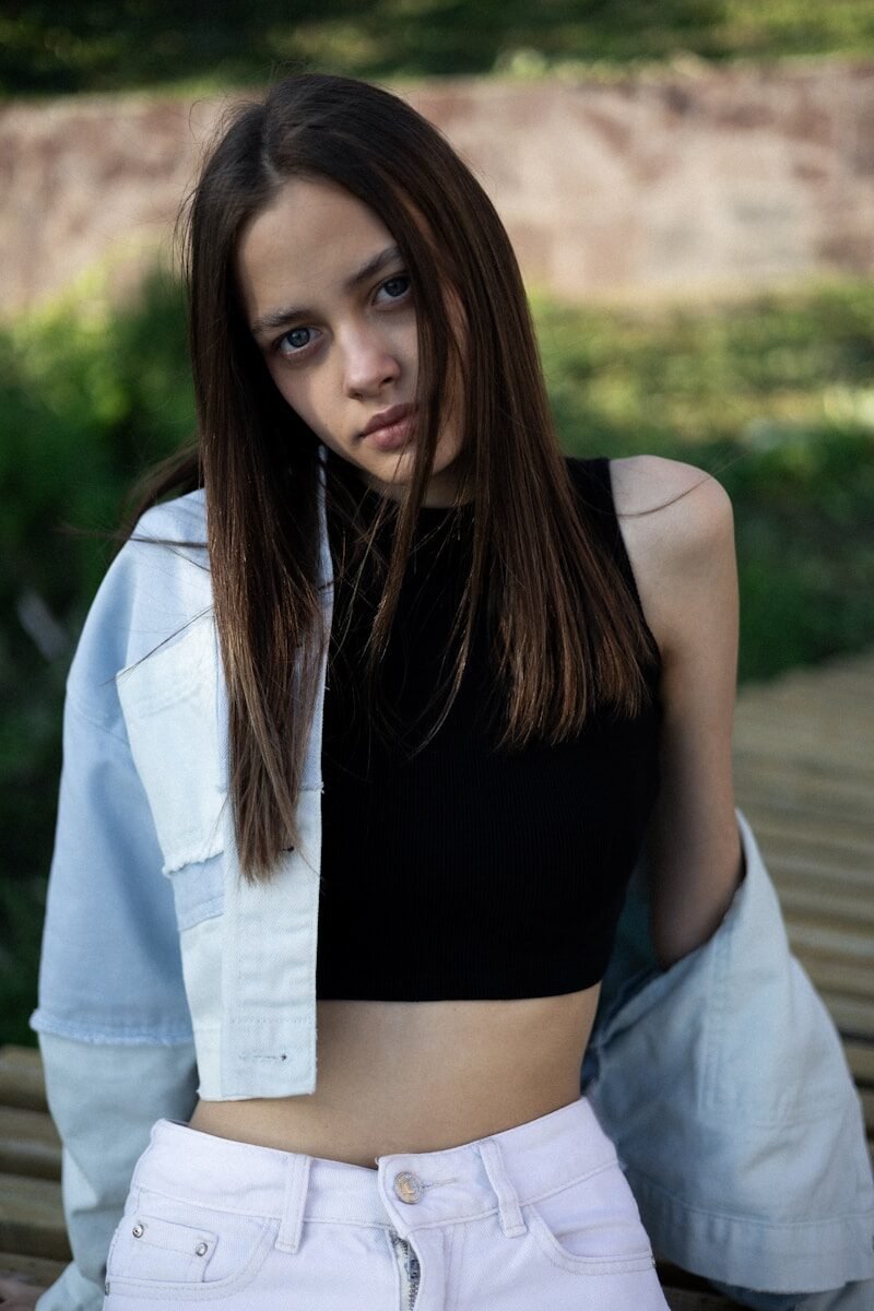 A young woman poses, looking directly at you.