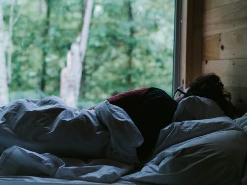 person lying on bed covered with blanket