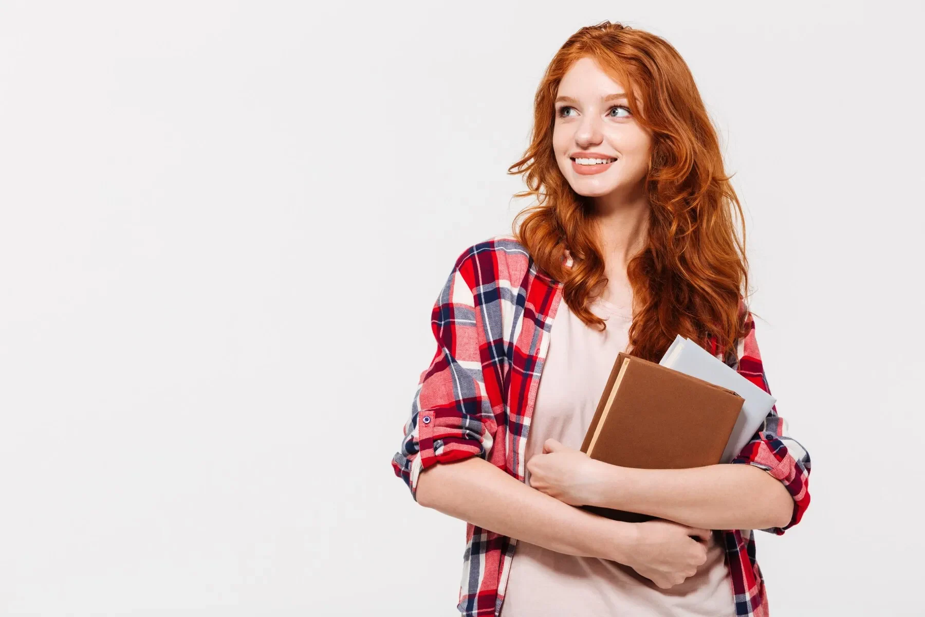 Pleased ginger woman shirt holding books looking away