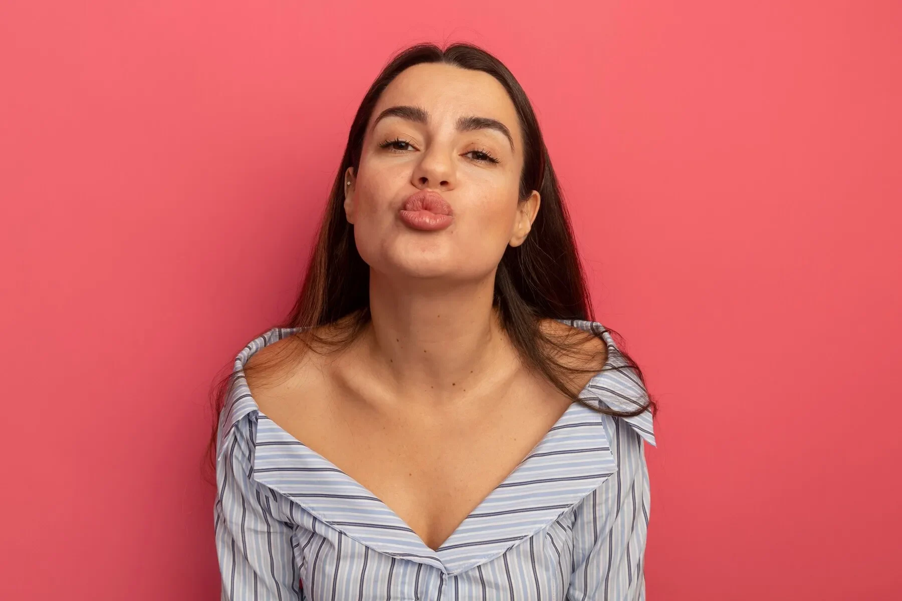 Pleased pretty woman pretends kiss isolated pink wall