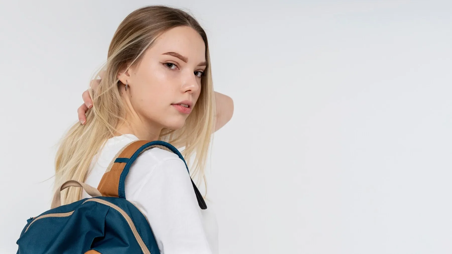 Portrait teen girl holding her backpack her hair pulled back