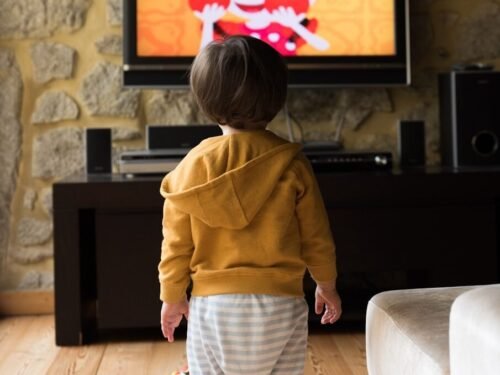 A small child standing in front of a television