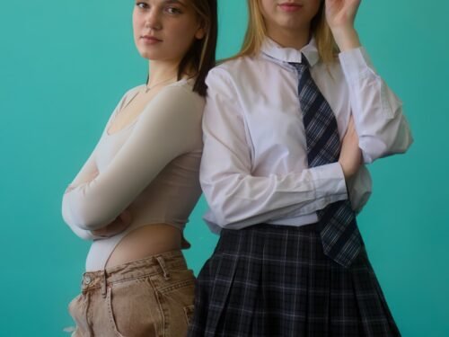 Two young women pose in front of a blue background.