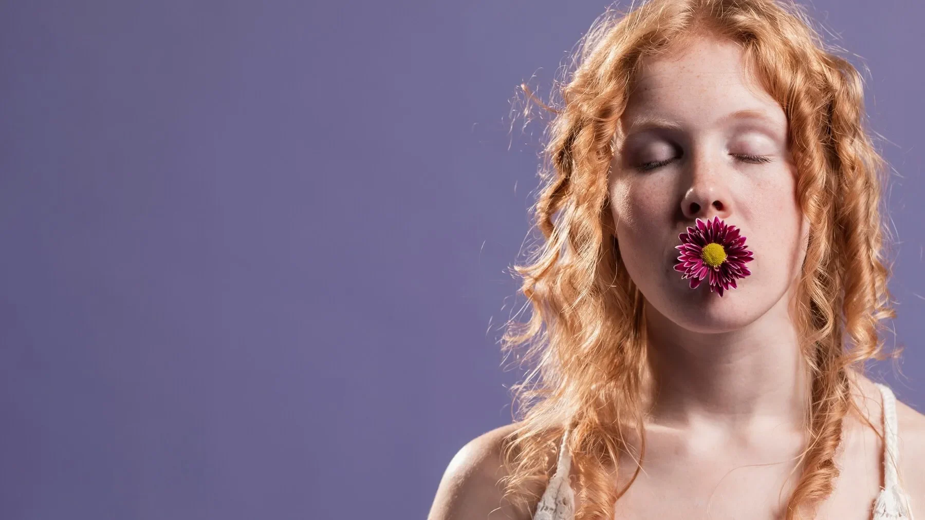 Redhead woman posing with flower her mouth