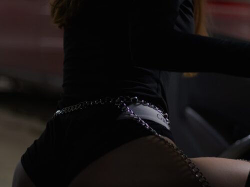 woman in black long sleeve shirt and black shorts sitting on black leather seat