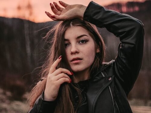 woman in black leather jacket standing on brown field during daytime