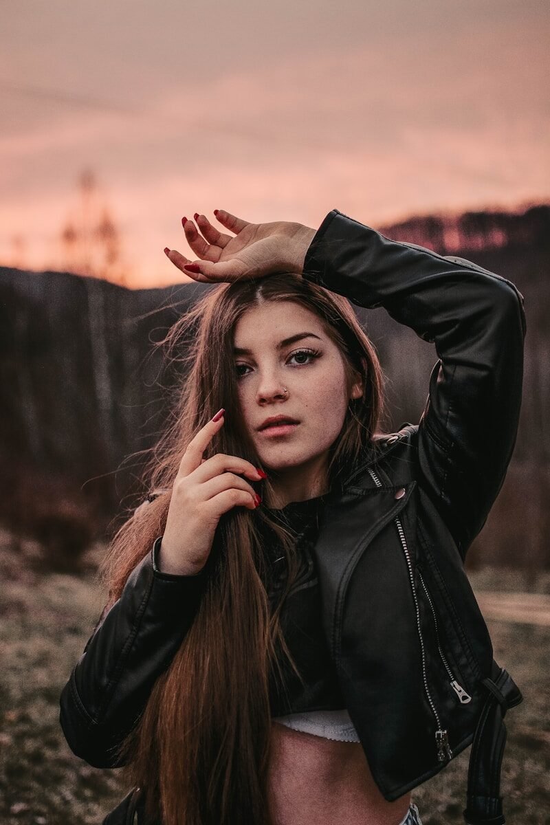 woman in black leather jacket standing on brown field during daytime