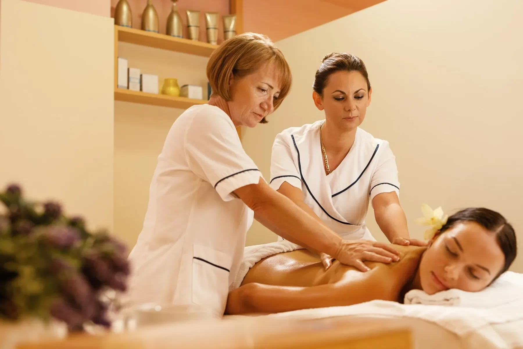 Serene woman getting back massage by two therapists spa treatment