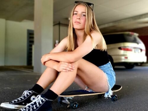 a girl sitting on a skateboard in a parking garage