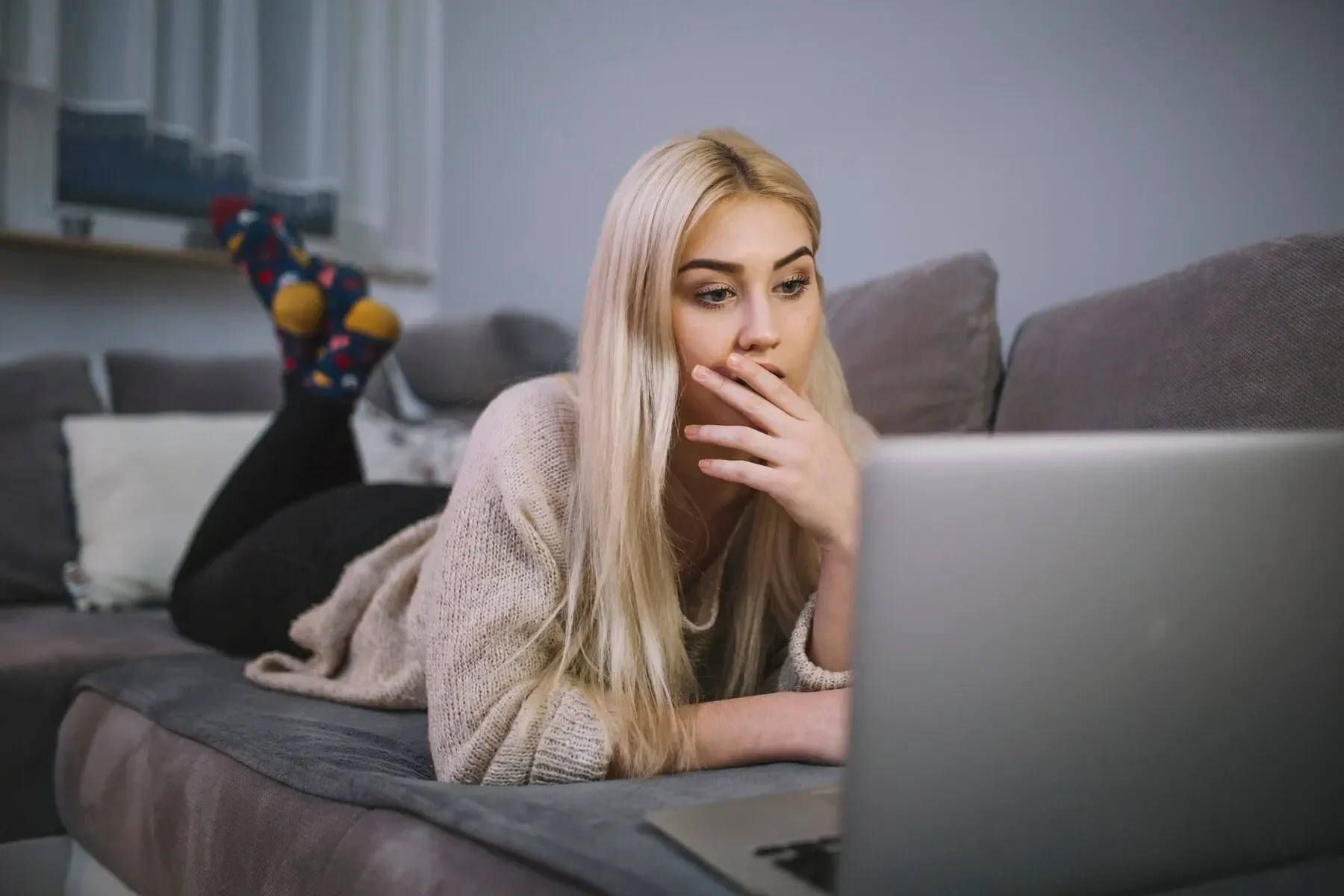 Shocked woman using laptop sofa