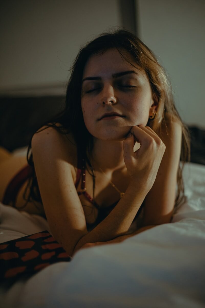 a woman laying on a bed with her eyes closed
