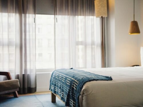 a hotel room with a bed, chair, and window