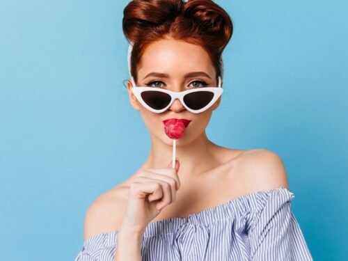 a woman wearing sunglasses holding a lollipop in front of her face