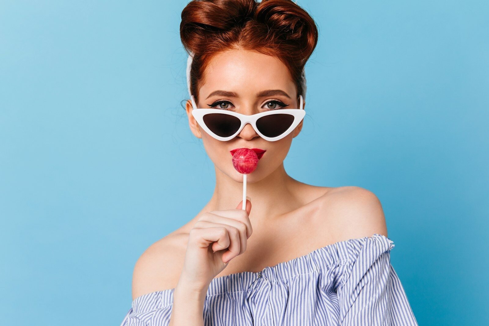 a woman wearing sunglasses holding a lollipop in front of her face