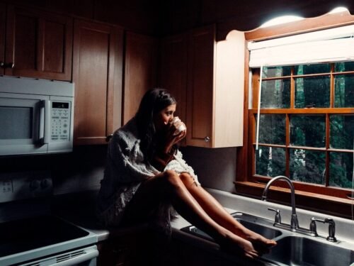woman in black dress sitting on kitchen sink