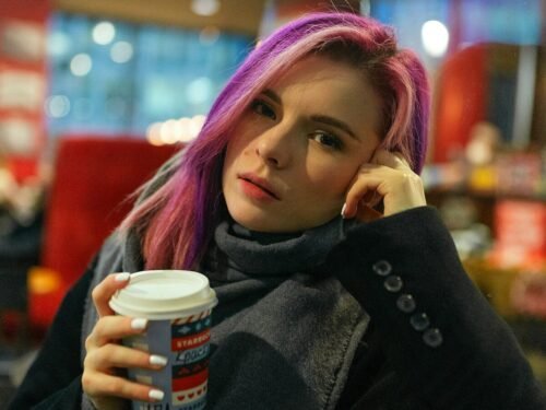 woman in black coat holding white and brown disposable cup