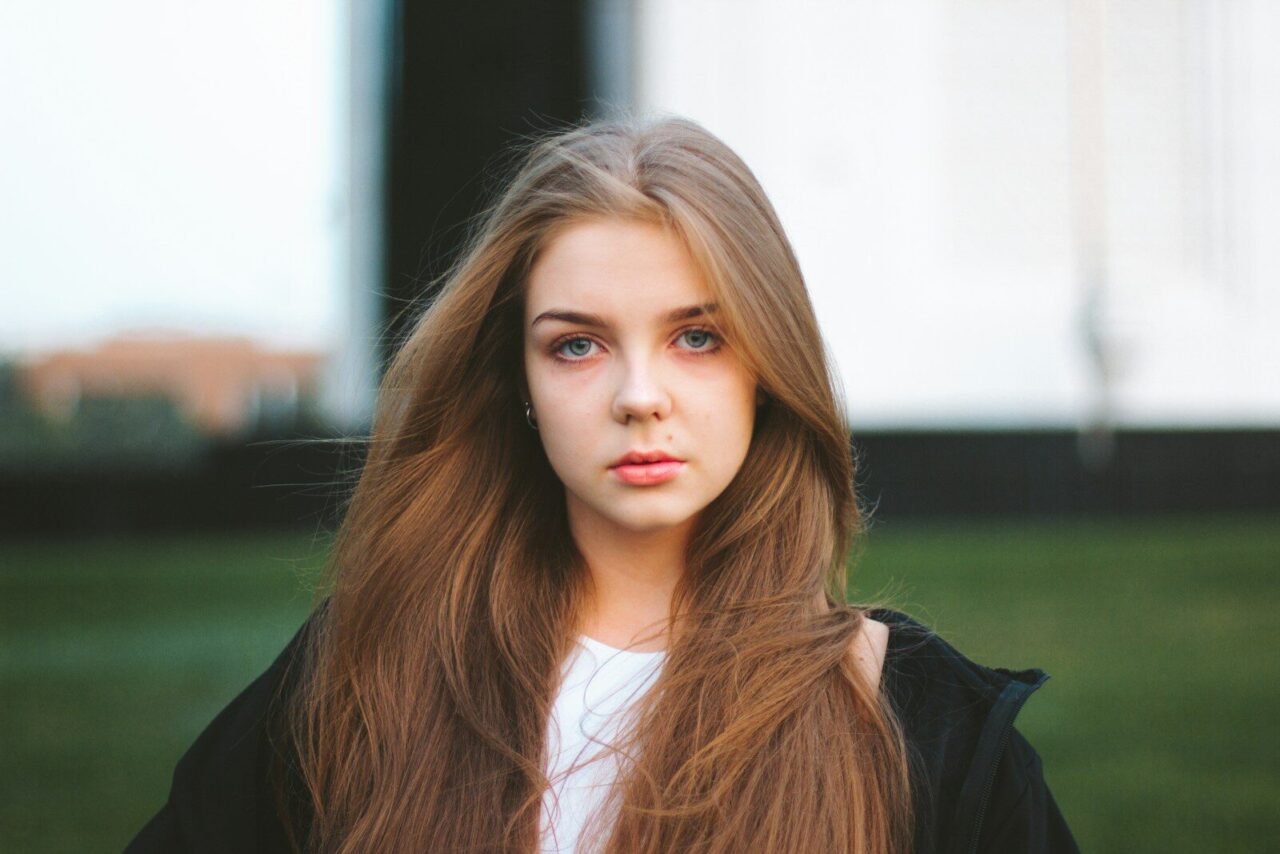 a woman with long hair standing in a field