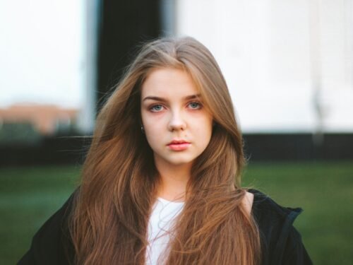 a woman with long hair standing in a field