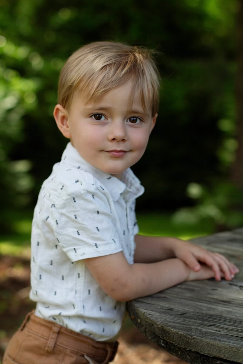 A young boy leaning on a picnic table