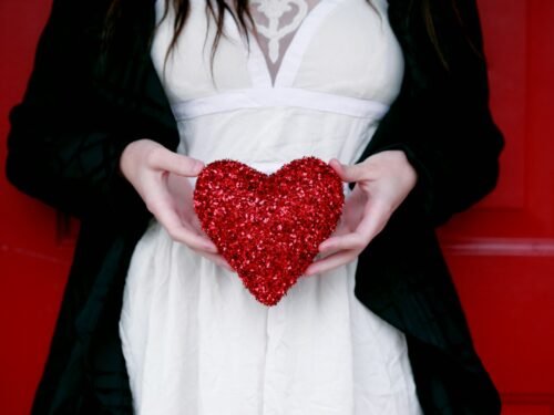women holding red heart pillow