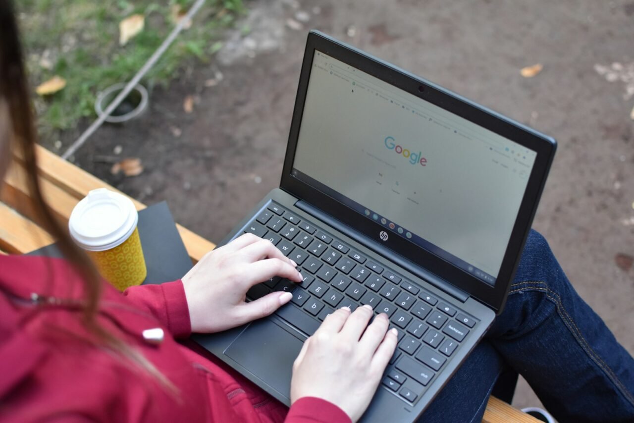 a woman sitting on a bench using a laptop computer