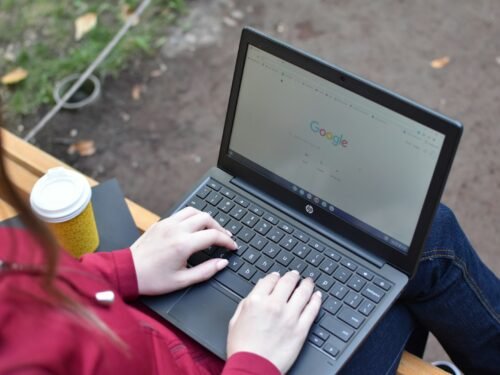 a woman sitting on a bench using a laptop computer