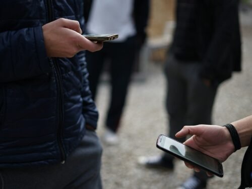person in black jacket holding white smartphone