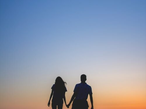 man and woman holding hands in silhouette photography