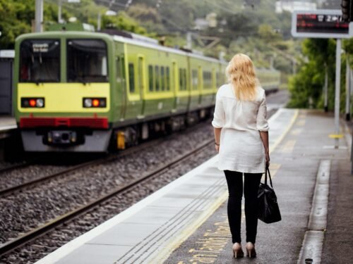a woman walking down a train track next to a train