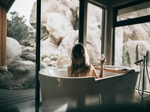 woman in white bathtub holding clear drinking glass