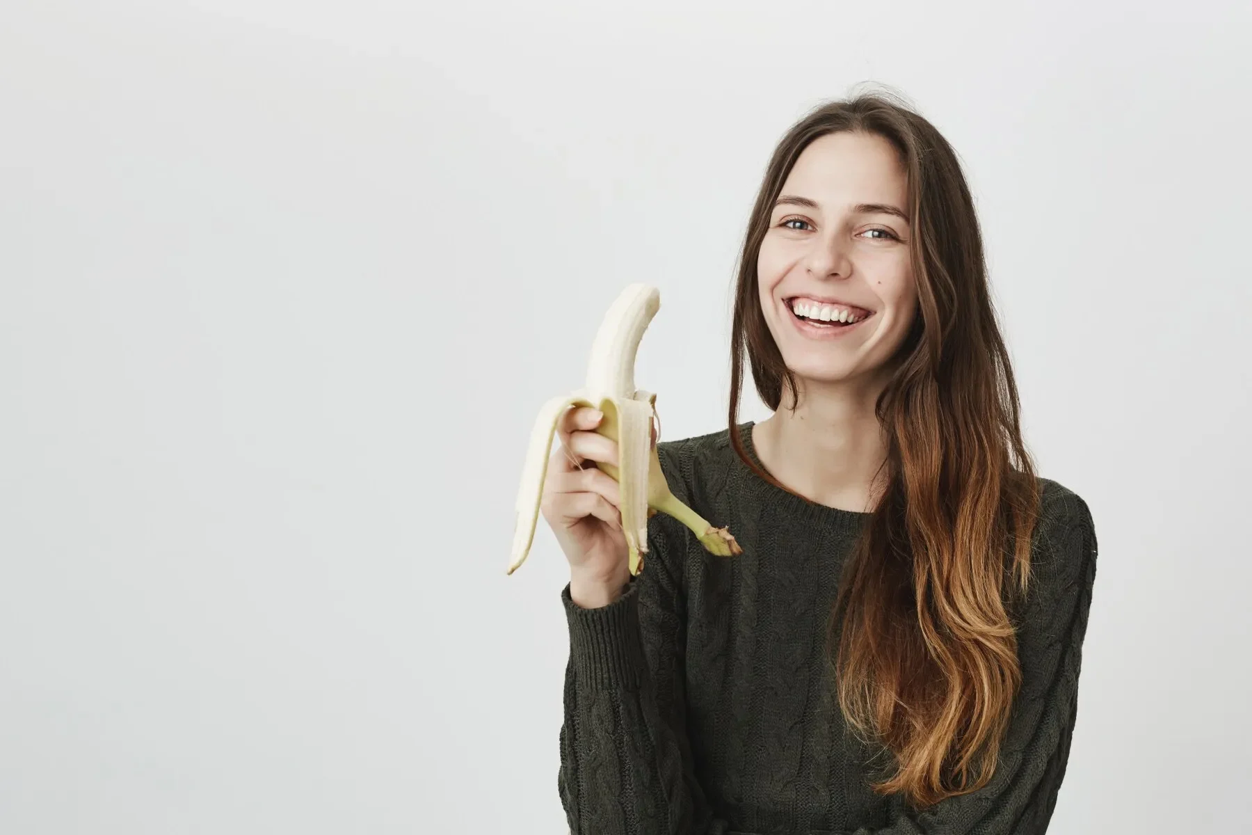 Young happy woman eating banana laughing