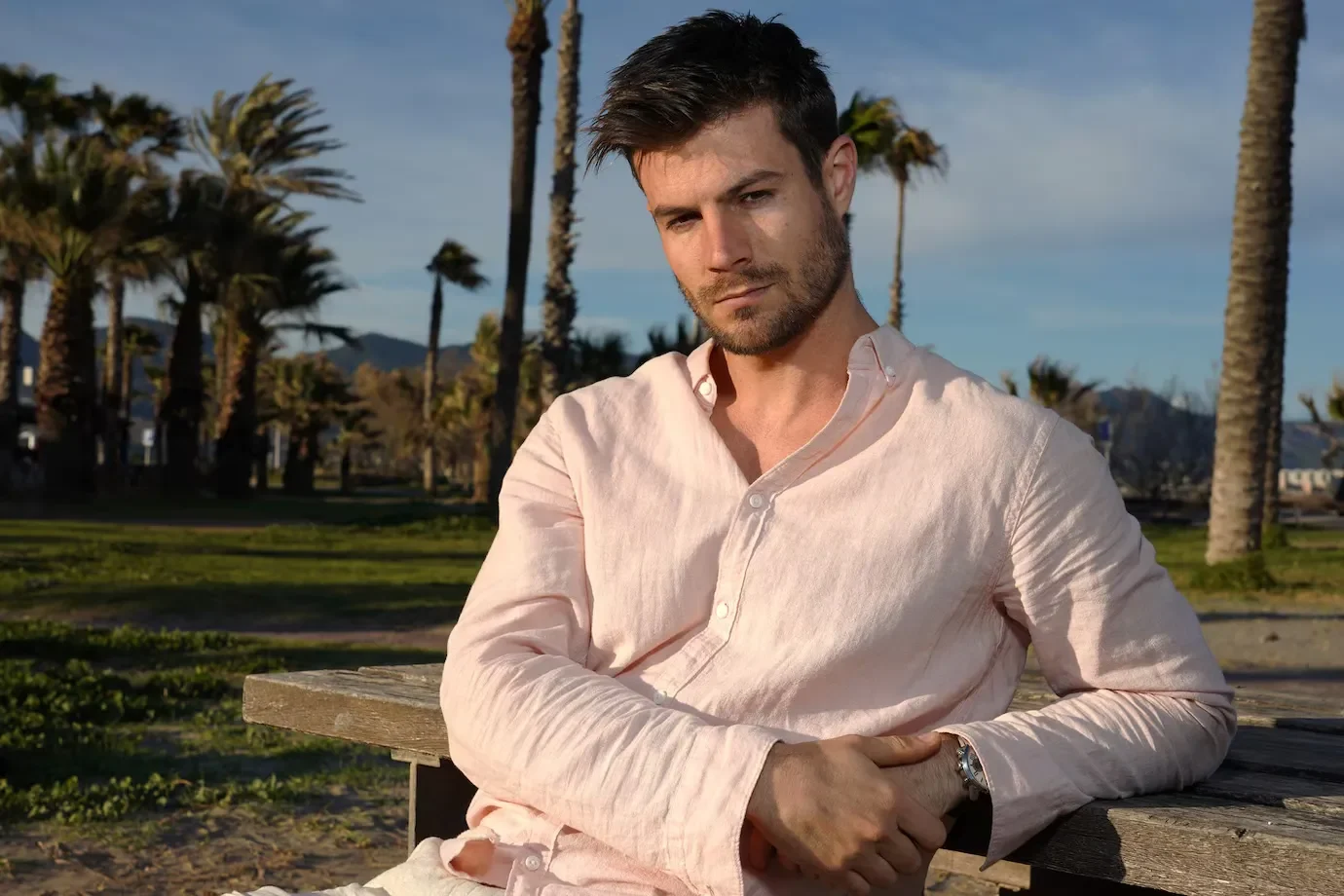 Young hispanic male wearing pink shirt posing beach